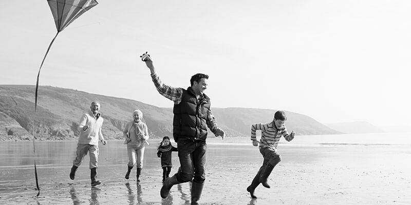 Three generations of a family flying a kite on a beach