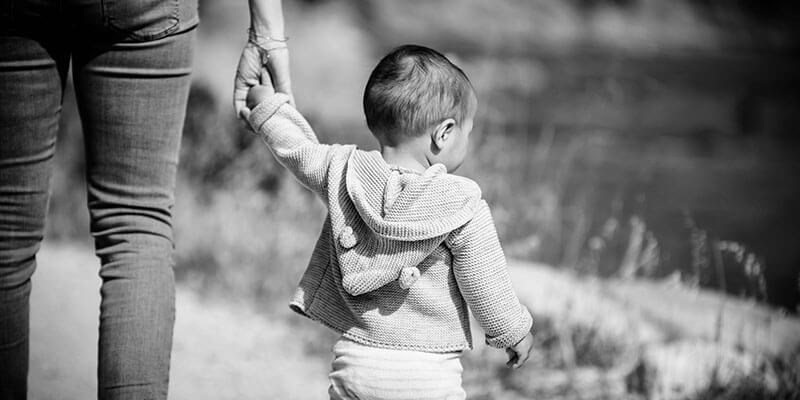 Parent holding hands with toddler in the countryside