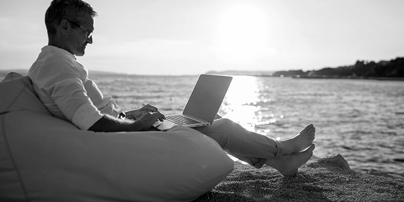 Relaxed man working on his laptop with a view of the sea