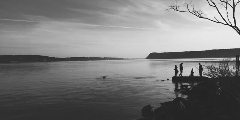 Wide open lake with silhouettes of people on small jetty