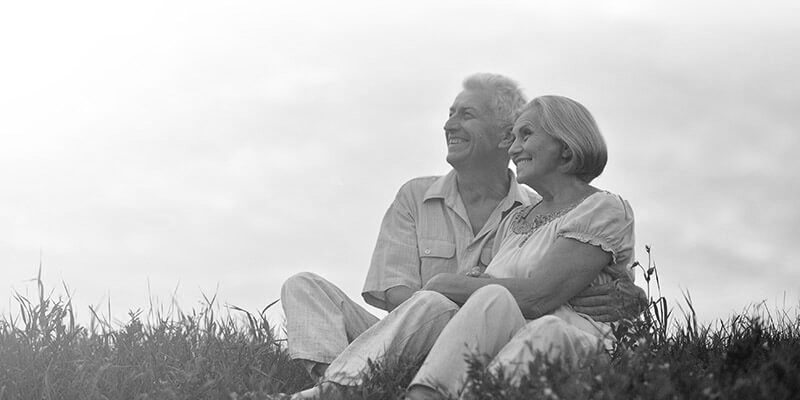 Happy retired couple sat on on the grass