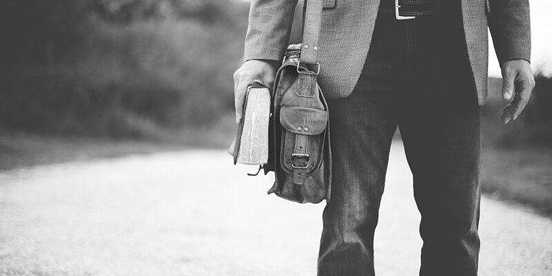 Partial view of smartly dresses man carrying a bag and a book