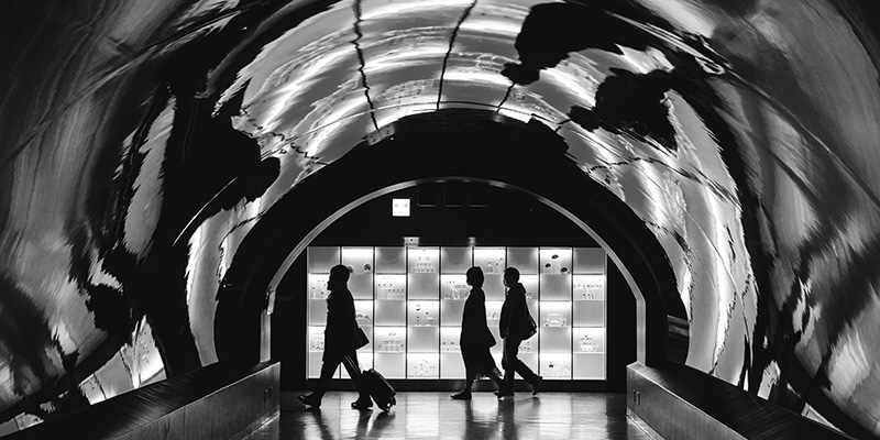 Silhouette of three people walking past a lit up display