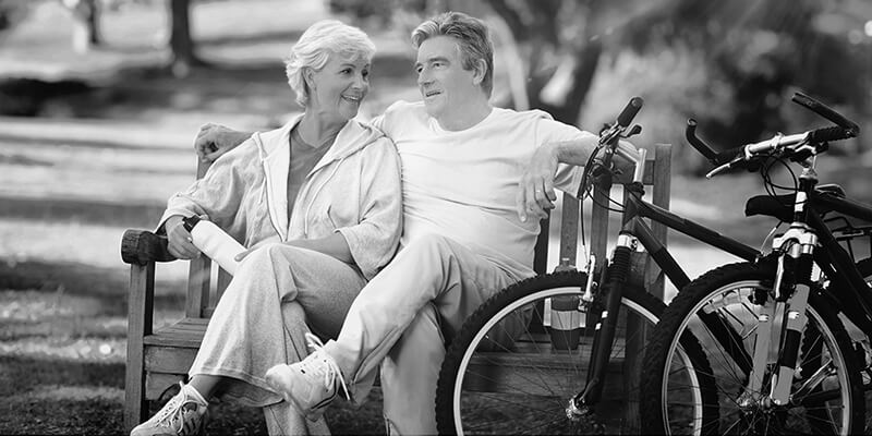 Retired couple sat on a bench taking a break from cycling