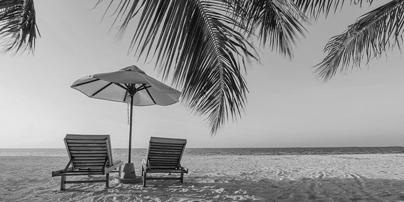 Two empty sun lounges and a parasol on a tropical sandy beach