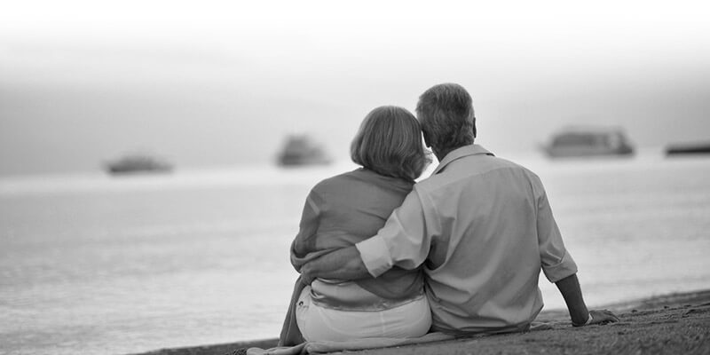 Retired couple sat on a beach looking out at the ocean